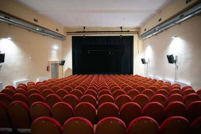 Interior del auditorio con butacas rojas dispuestas en gradas frente al escenario