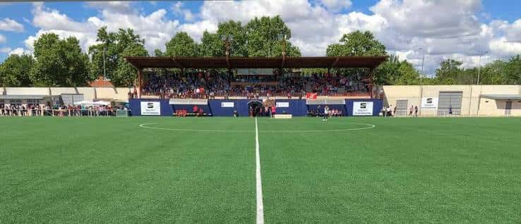 Vista panorámica del campo de fútbol con grada cubierta y césped artificial