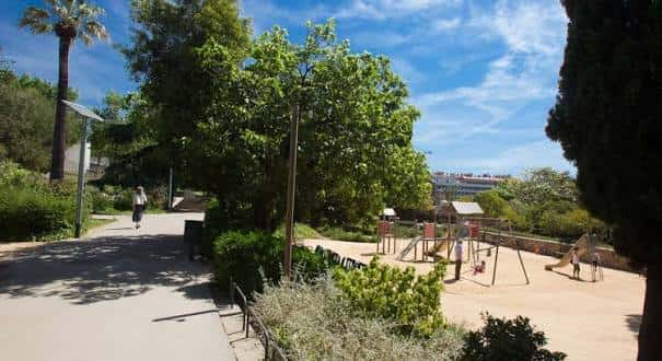Área recreativa infantil con columpios en el parque bajo un cielo azul