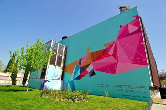 Fachada lateral del centro cultural con mural geométrico colorido bajo cielo azul
