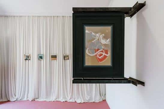Interior de la galería con cortinas blancas y obra de arte colgante