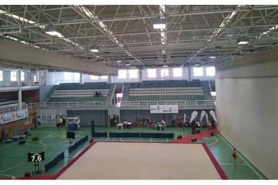 Vista general del interior del pabellón con pista de voleibol montada y gradas vacías