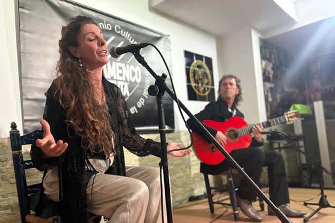 Artista cantando flamenco en el escenario acompañada por un guitarrista