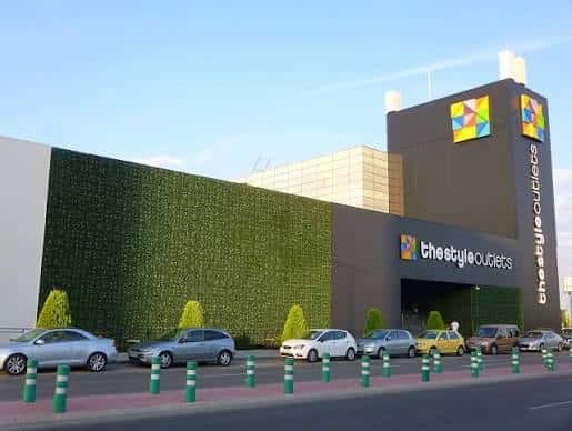 Fachada lateral del centro comercial con pared verde y entrada principal