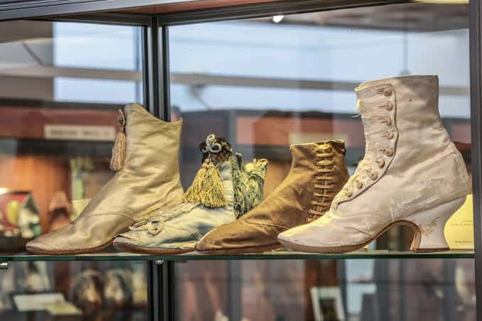 Exposición de botas históricas en vitrina del museo