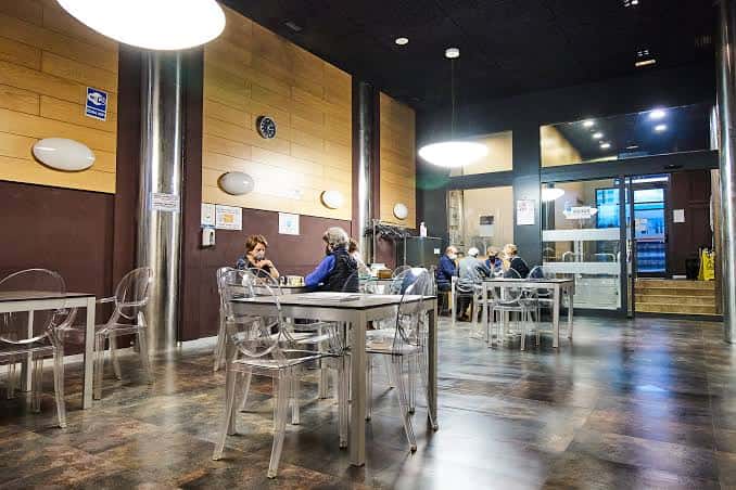 Interior del salón de Erdialde Elkartea con mesas y sillas transparentes