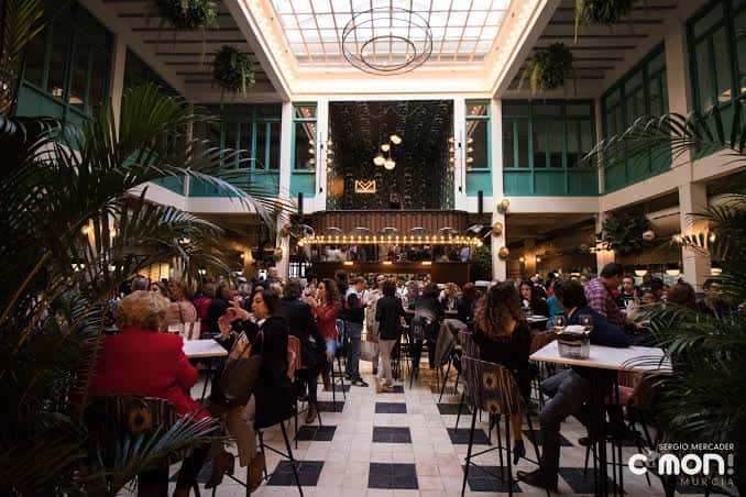 Interior del Mercado de Correos con ambiente festivo y decoración tropical
