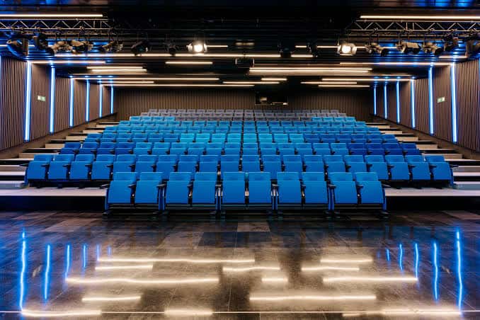 Interior del auditorio con butacas azules y escenario