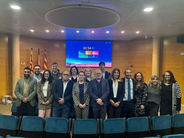 Interior del auditorio de la ICAT con grupo de personas posando frente a pantalla digital