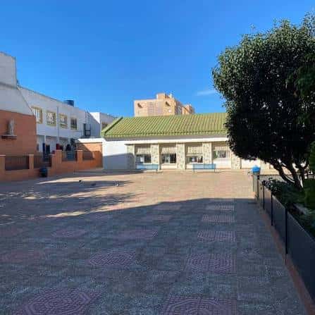 Patio exterior del colegio con suelo de baldosas y cielo despejado