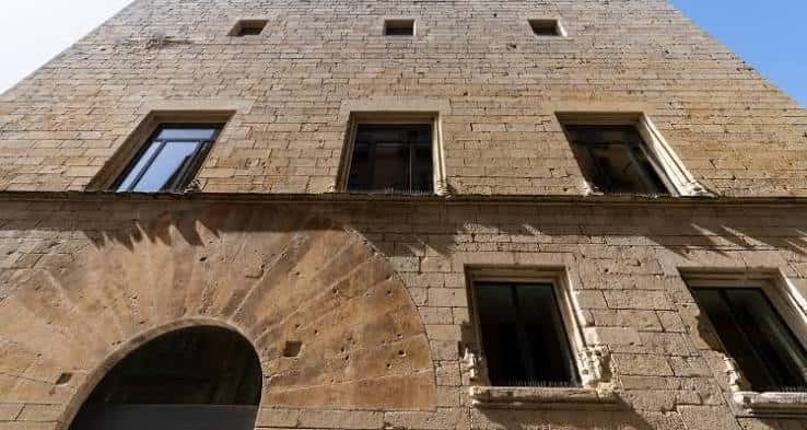 Detalle arquitectónico de la fachada de piedra con ventanas y arco de entrada
