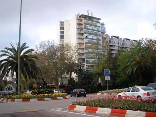 Plaza circular en la Avenida de España con jardines y rascacielos al fondo