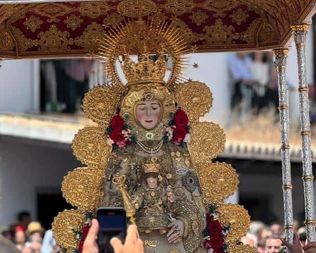 Vista frontal de la Virgen del Rocío en su andor, con corona y manto ricamente adornados