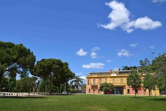 Vista panorámica del edificio principal de Mas Miarnau rodeado de jardines y árboles bajo un cielo azul