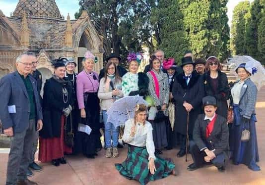 Grupo de personas disfrazadas posando frente a una cripta gótica en el cementerio