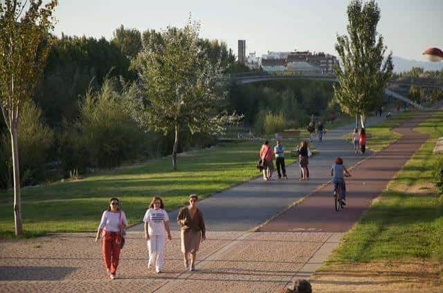 Paseo del Parque en León con senderos peatonales y ciclistas bajo la luz de la tarde
