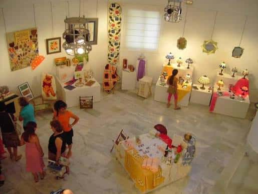 Interior de la sala de exposiciones con visitantes y obras artísticas