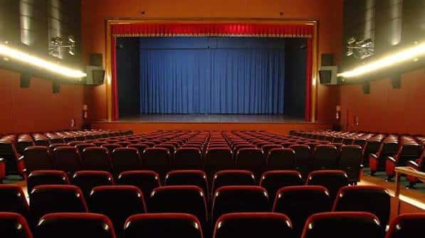 Vista general del interior del Teatro Salesianos con butacas rojas y escenario con telón azul