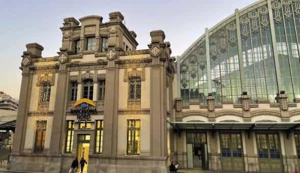 Fachada principal de la estación al atardecer, mostrando detalles arquitectónicos y entrada iluminada