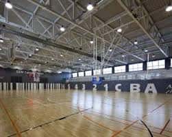 Pista de baloncesto interior con canastas y suelo de madera