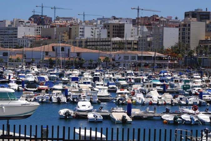 Puerto deportivo lleno de barcos con edificios urbanos en el fondo