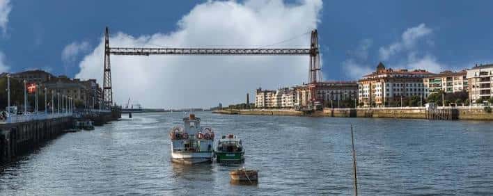 Puente Bizkaia con barcos navegando por debajo en una escena diurna tranquila