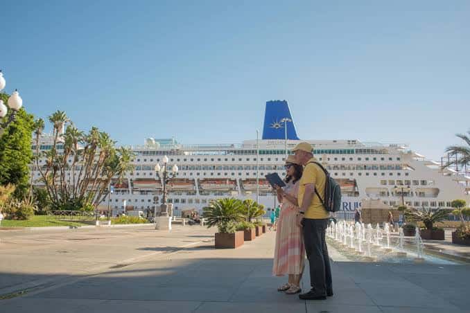 Paseo marítimo junto al puerto con crucero atracado al fondo