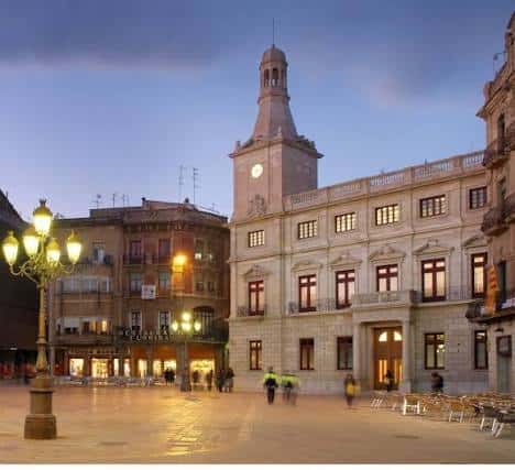 Vista nocturna del Palau Municipal con la fachada iluminada y plaza vacía