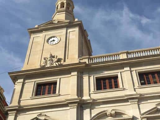 Detalle arquitectónico de la torre del reloj del Palau Municipal bajo cielo azul