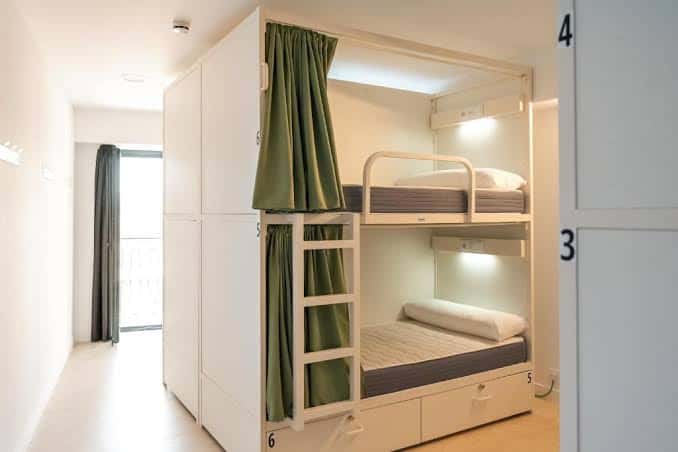 Habitación con literas modernas y cortinas verdes para privacidad