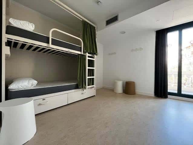 Interior espacioso de habitación con literas y acceso a balcón