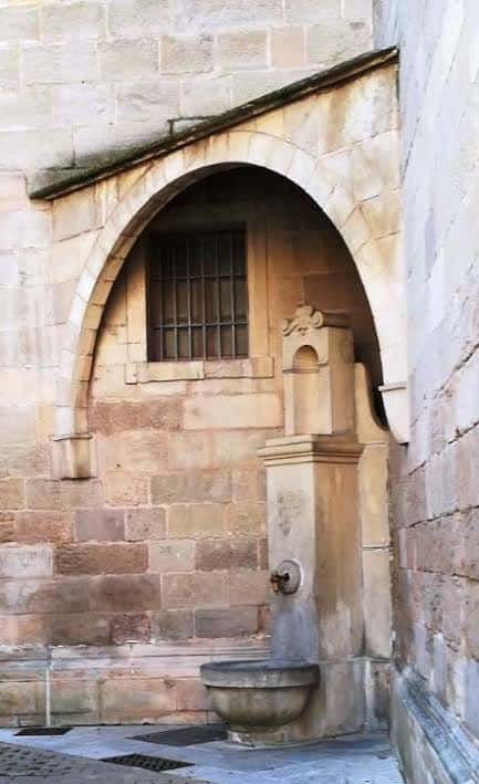 Vista frontal de la Font Vella en Igualada con arco de piedra y fuente central