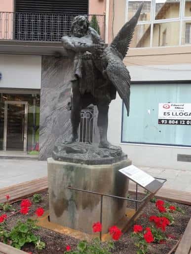 Escultura de Hèrcules en el centro de la Plaça del Pilar rodeada de flores