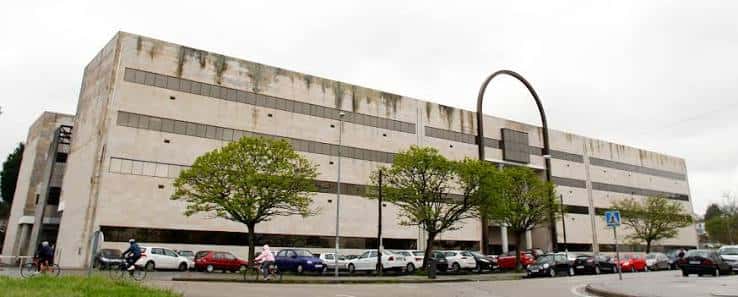 Fachada principal del edificio universitario con árboles y aparcamiento