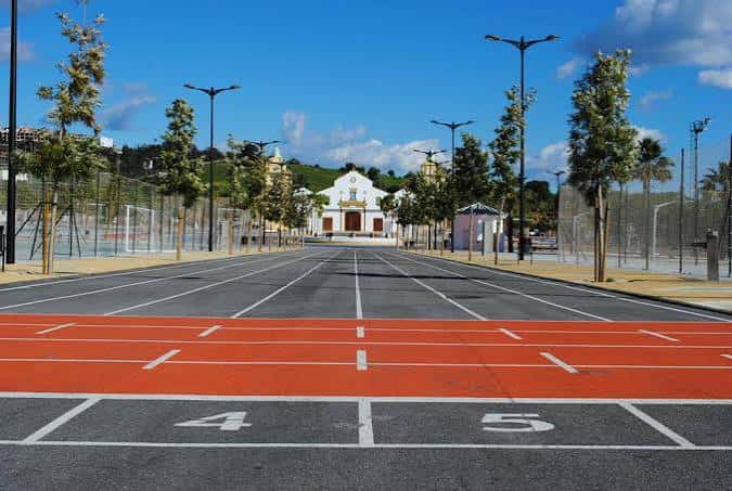 Pista de atletismo en primer plano con edificio blanco al fondo bajo cielo azul
