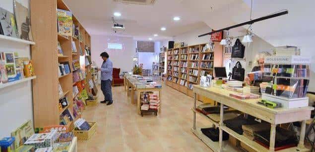 Interior de la librería con estanterías llenas de libros y un cliente navegando