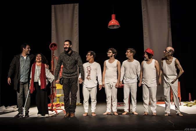 Actuación teatral con elenco completo en escena bajo iluminación dramática