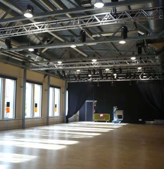 Interior del espacio escénico con iluminación profesional y suelo de madera