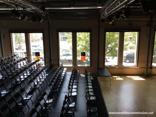 Sala de eventos con butacas dispuestas para audiencia y escenario al frente