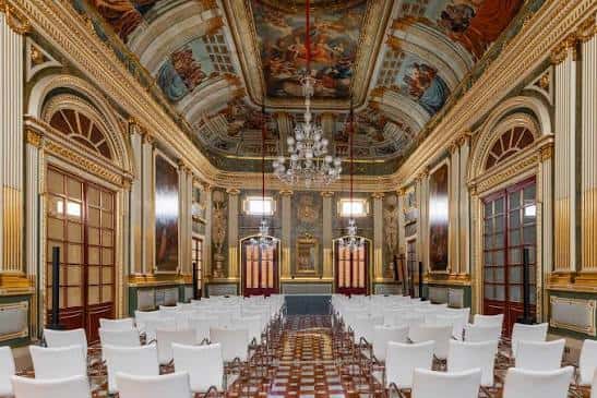 Sala principal del Palau Bofarull decorada para un evento con sillas blancas y techo pintado