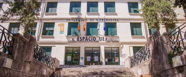 Fachada principal del Espacio UEx en Cáceres con escaleras y banderas