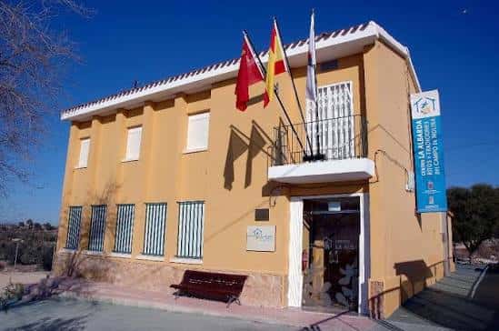 Vista exterior del Centro La Albarda con fachada amarilla y banderas