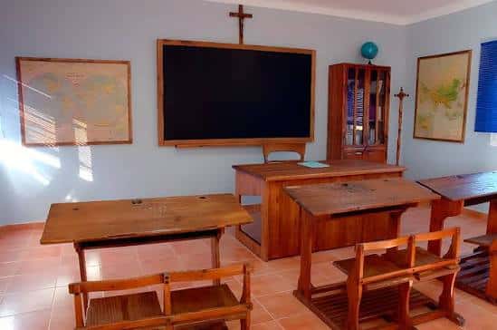 Interior de aula tradicional con pupitres de madera y pizarra