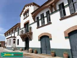 Fachada principal de la granja con arquitectura tradicional catalana, balcones y puertas de madera