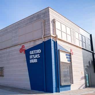 Detalle de la esquina del edificio mostrando el logotipo y la señalización azul