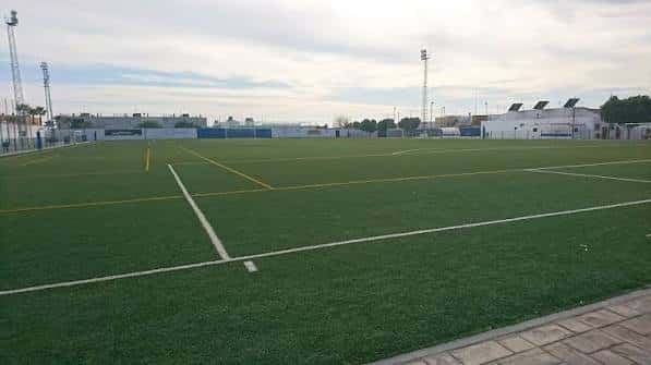 Campo de fútbol desde la línea lateral con portería y luces de iluminación