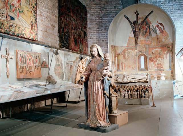 Interior del museo mostrando una estatua de la Virgen con el Niño y pinturas murales románicos