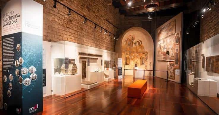 Sala de exposiciones con vitrinas de vidrio y muros de piedra antigua