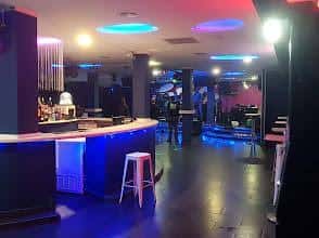 Interior del Soho Alternative Bar con barra iluminada y escenario