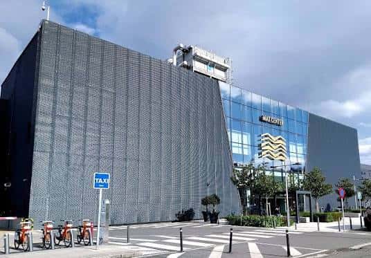 Vista exterior moderna del Max Center con fachada de vidrio y paneles metálicos
